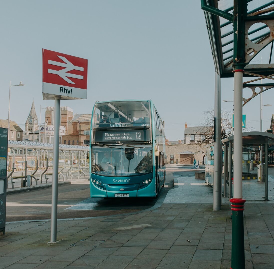 Bus station next to a train station with a double decker bus featured.